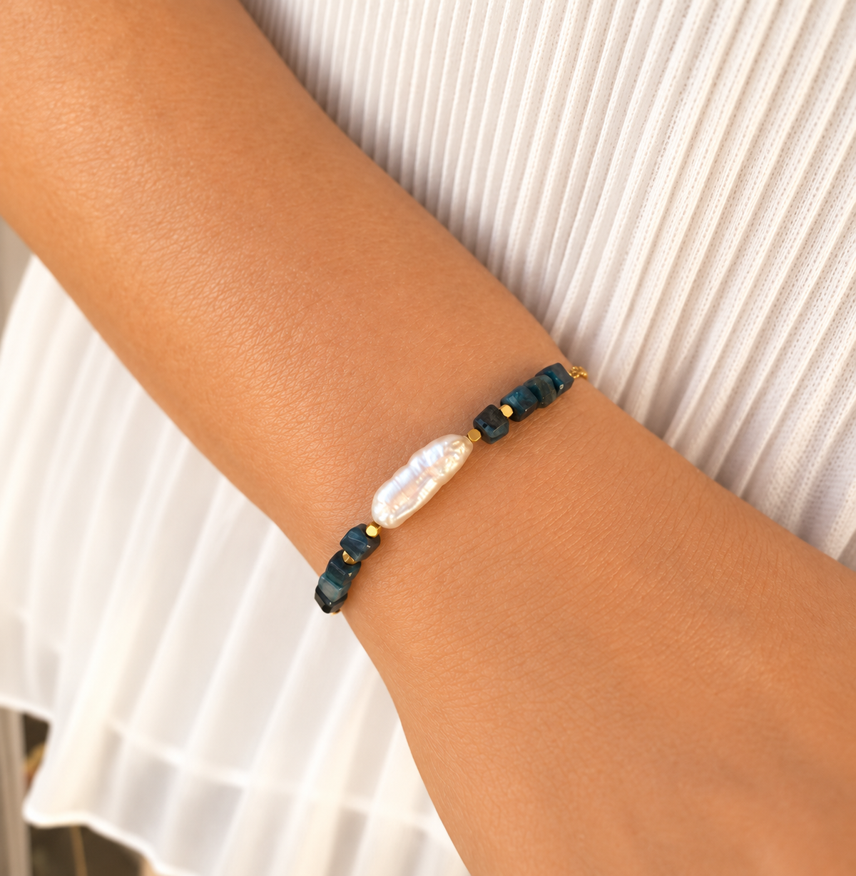 Pulsera AILA con perla barroca y ojo de tigre azul lago sobre muñeca