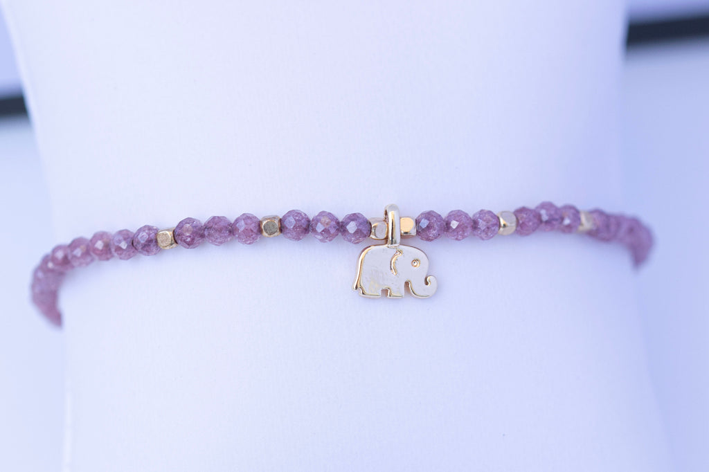  Detalle de pulsera elástica de circonita morada con elefante dorado
