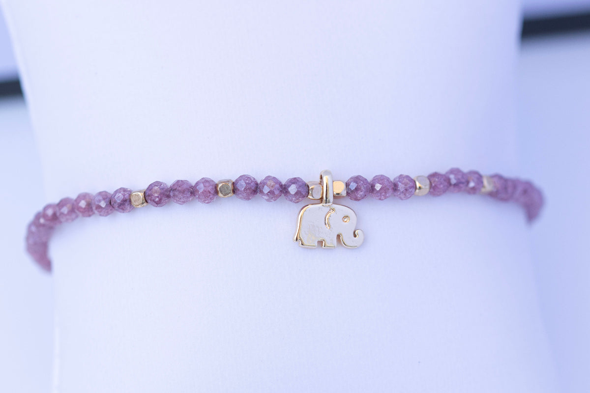  Detalle de pulsera elástica de circonita morada con elefante dorado
