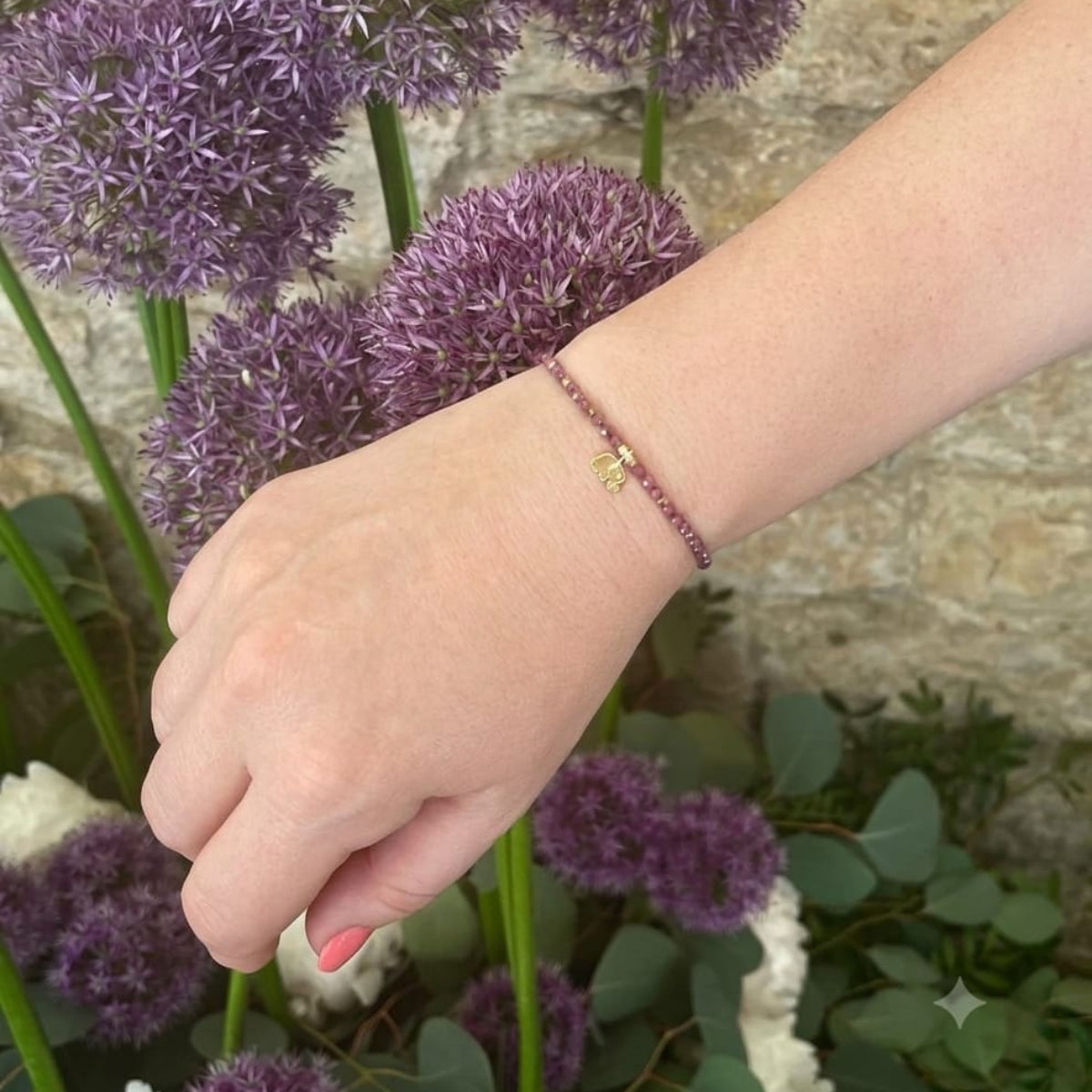  Pulsera de circonita morada y elefante dorado llevada en la muñeca

